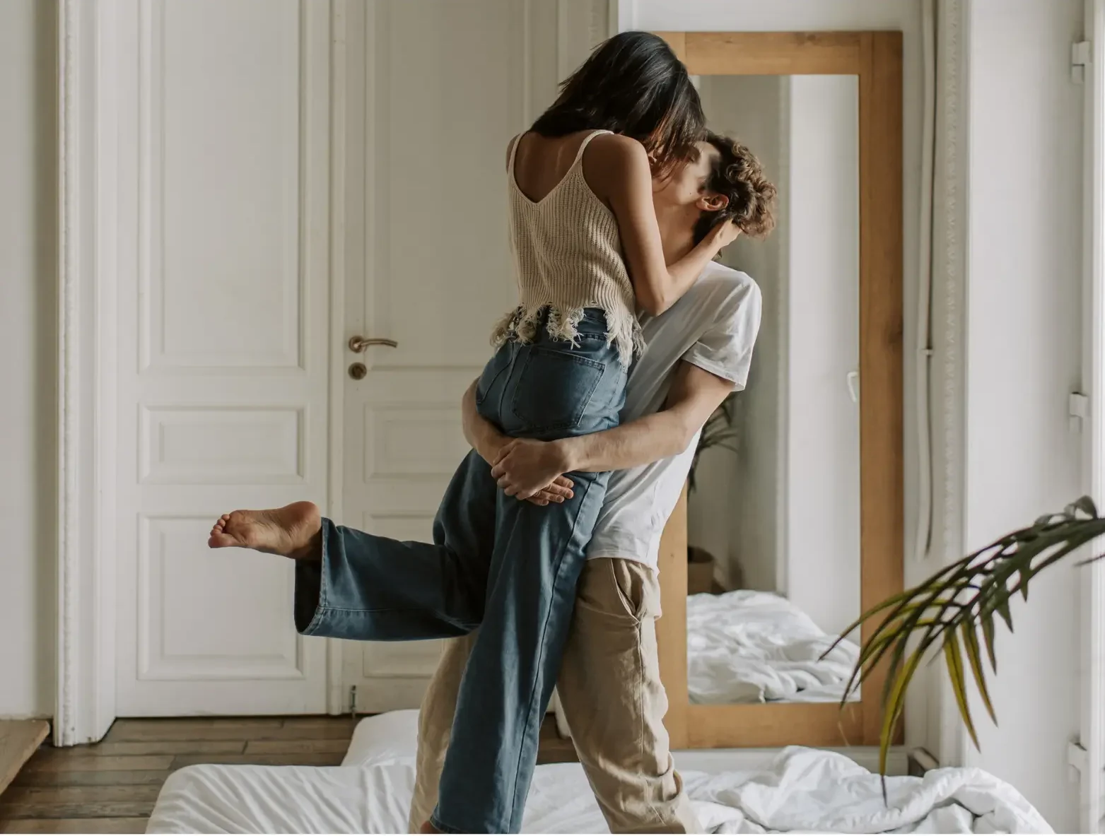 Ein Paar steht auf einem Bett. Der Mann hebt die Frau hoch. Die beiden küssen sich. Sie wollen ihre Beziehung retten.